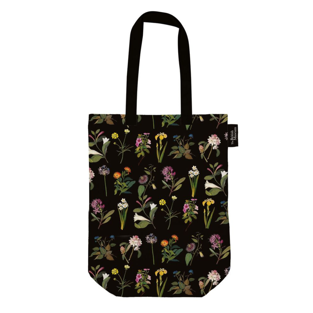 Black tote bag featuring a repeating pattern of colorful botanical illustrations on a dark background.