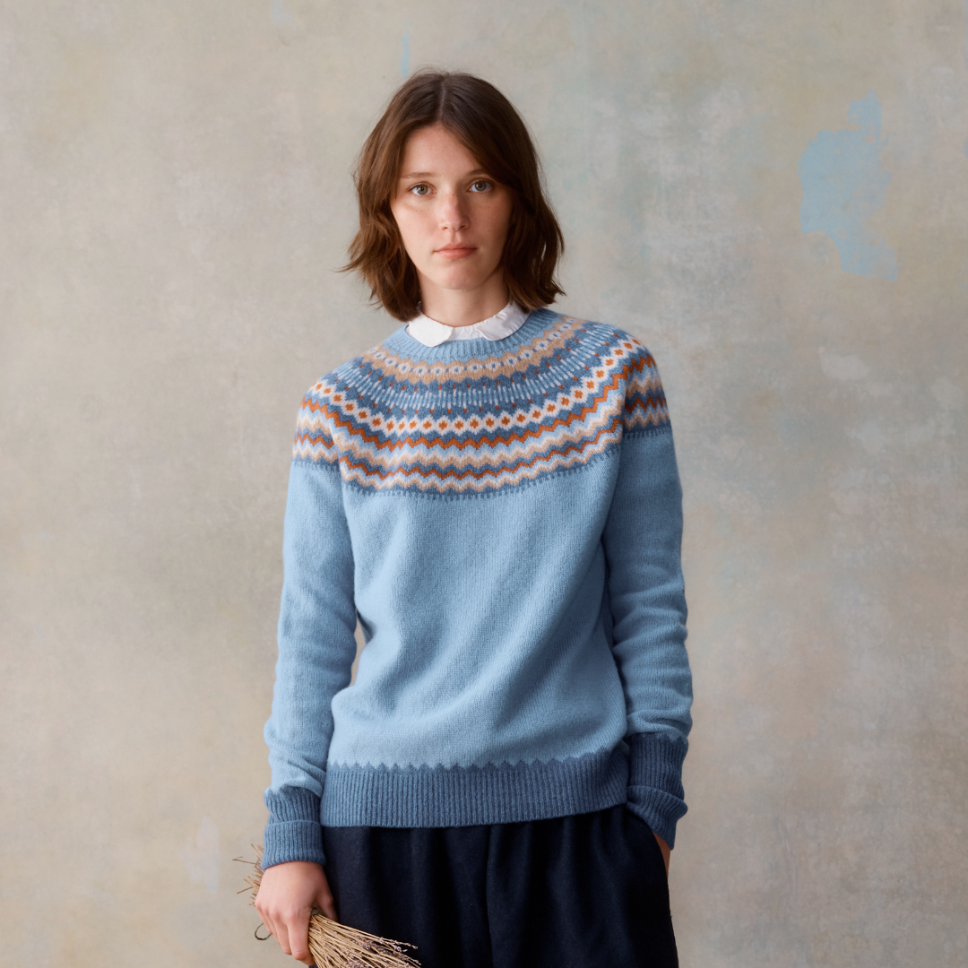 Light blue crewneck sweater with a Fair Isle-style yoke in muted orange, beige, and blue.