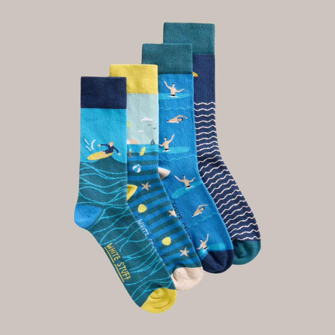 Four pairs of men's crew socks featuring summer beach scenes: surfing, swimming, and beach balls.