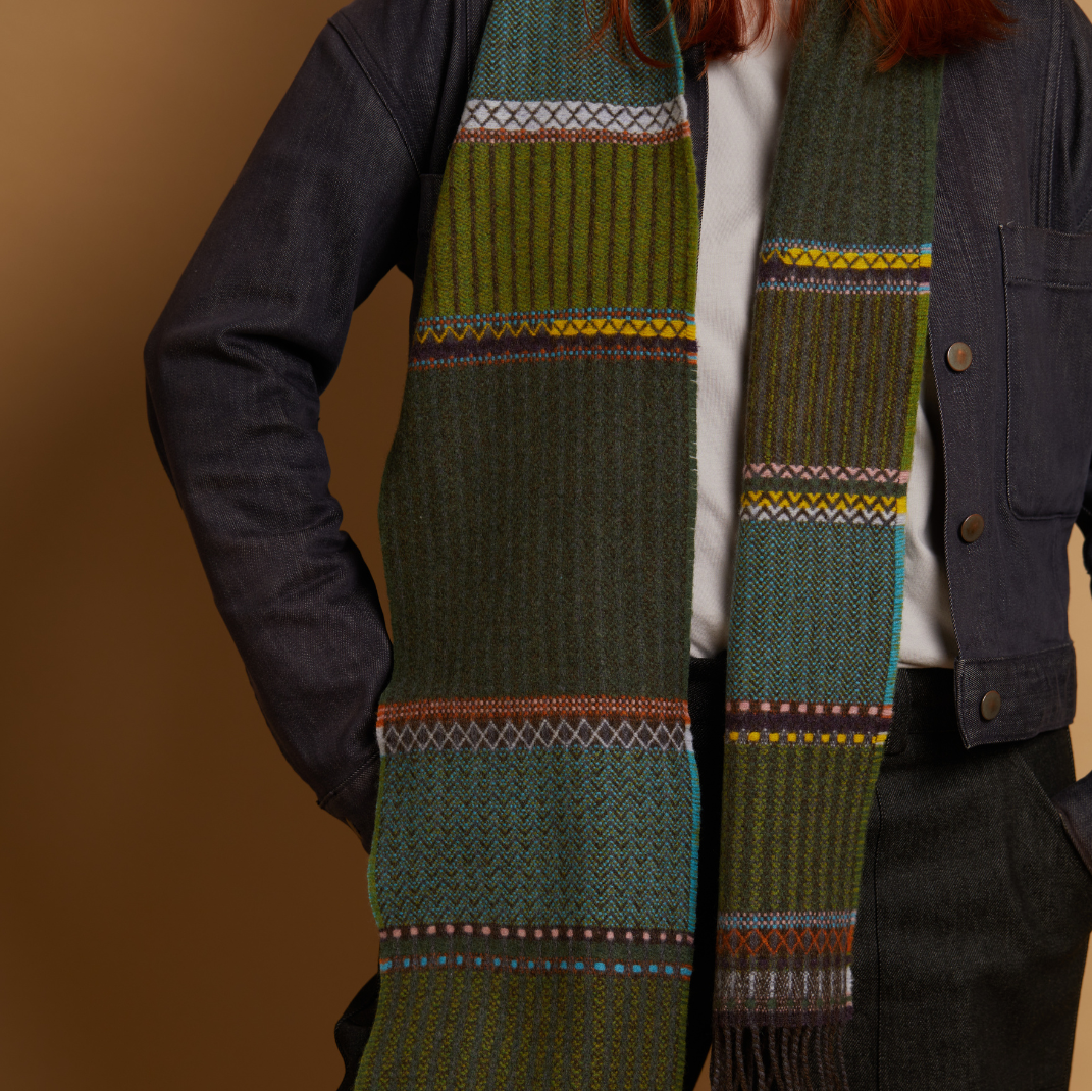 Person wearing a green patterned scarf with a brown background