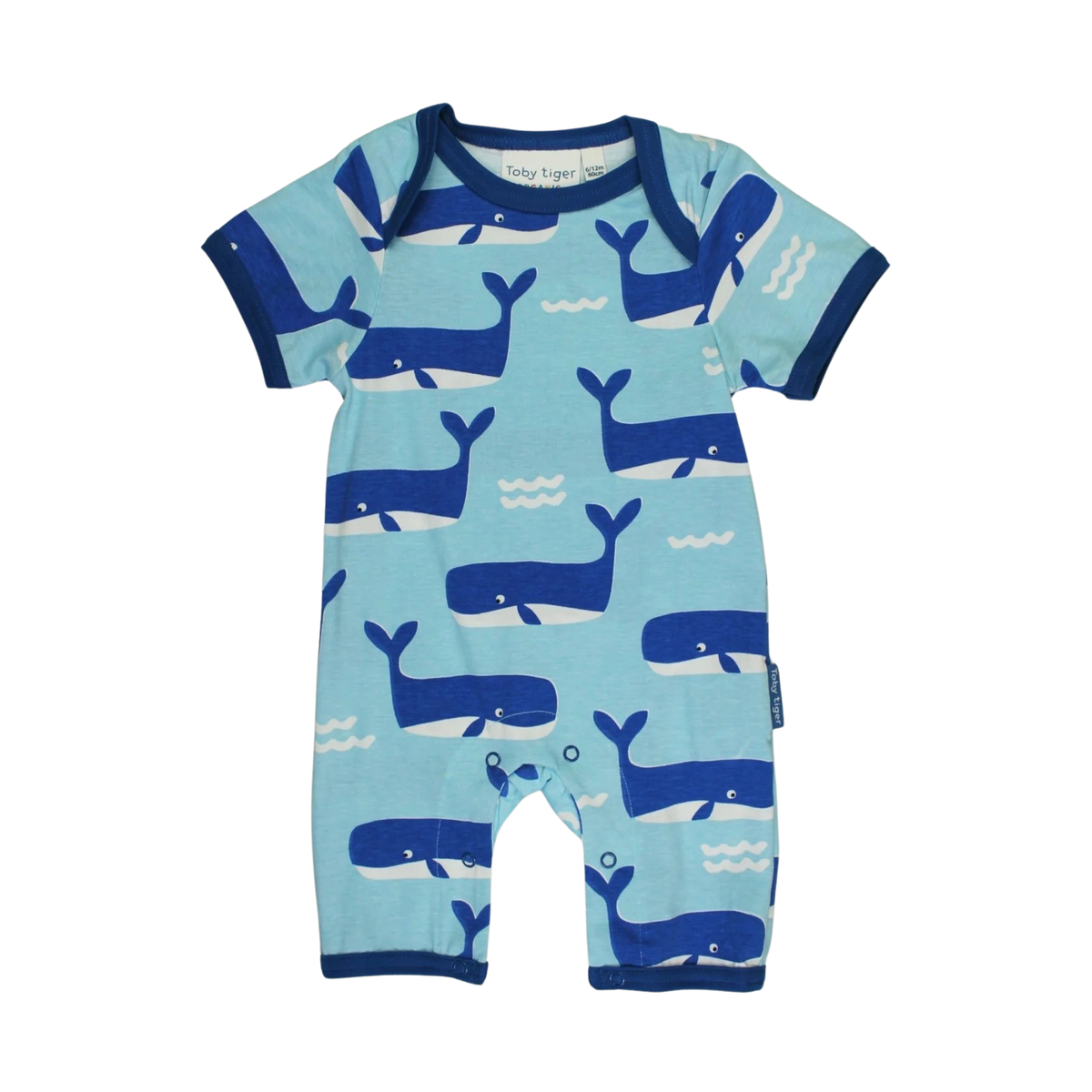 A baby short-sleeve romper in light blue with a navy blue whale pattern, featuring a snap-button closure at the crotch and ribbed trim.
