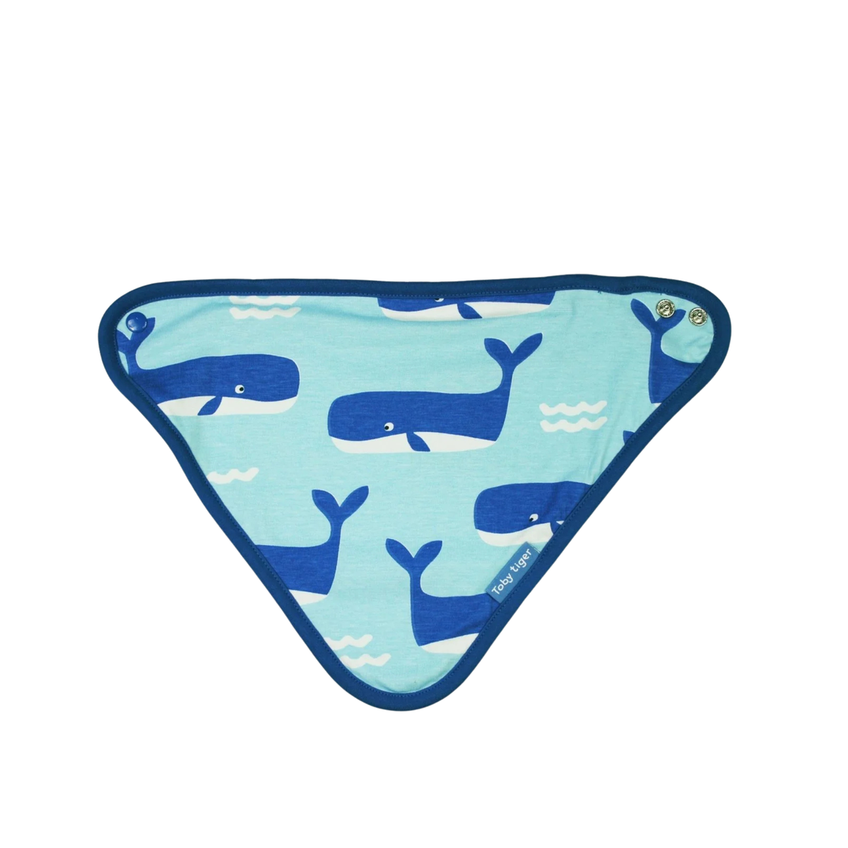 A triangular baby bib with a light blue background, featuring a pattern of dark blue whales and white waves, finished with a dark blue border.