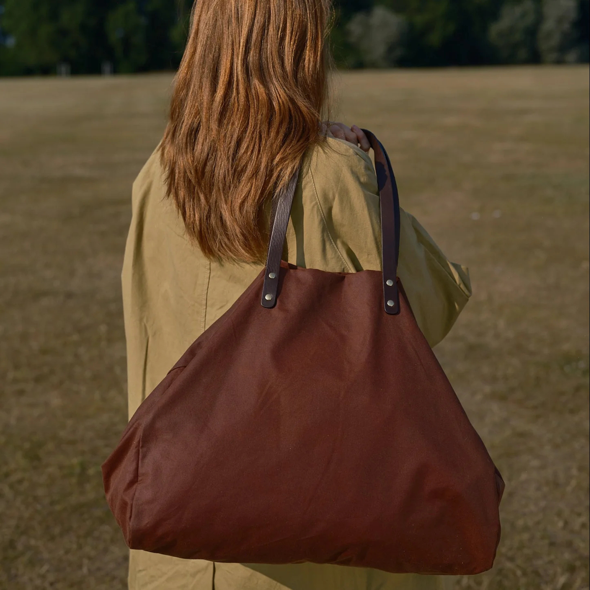 Person carrying a large brown bag in an outdoor setting