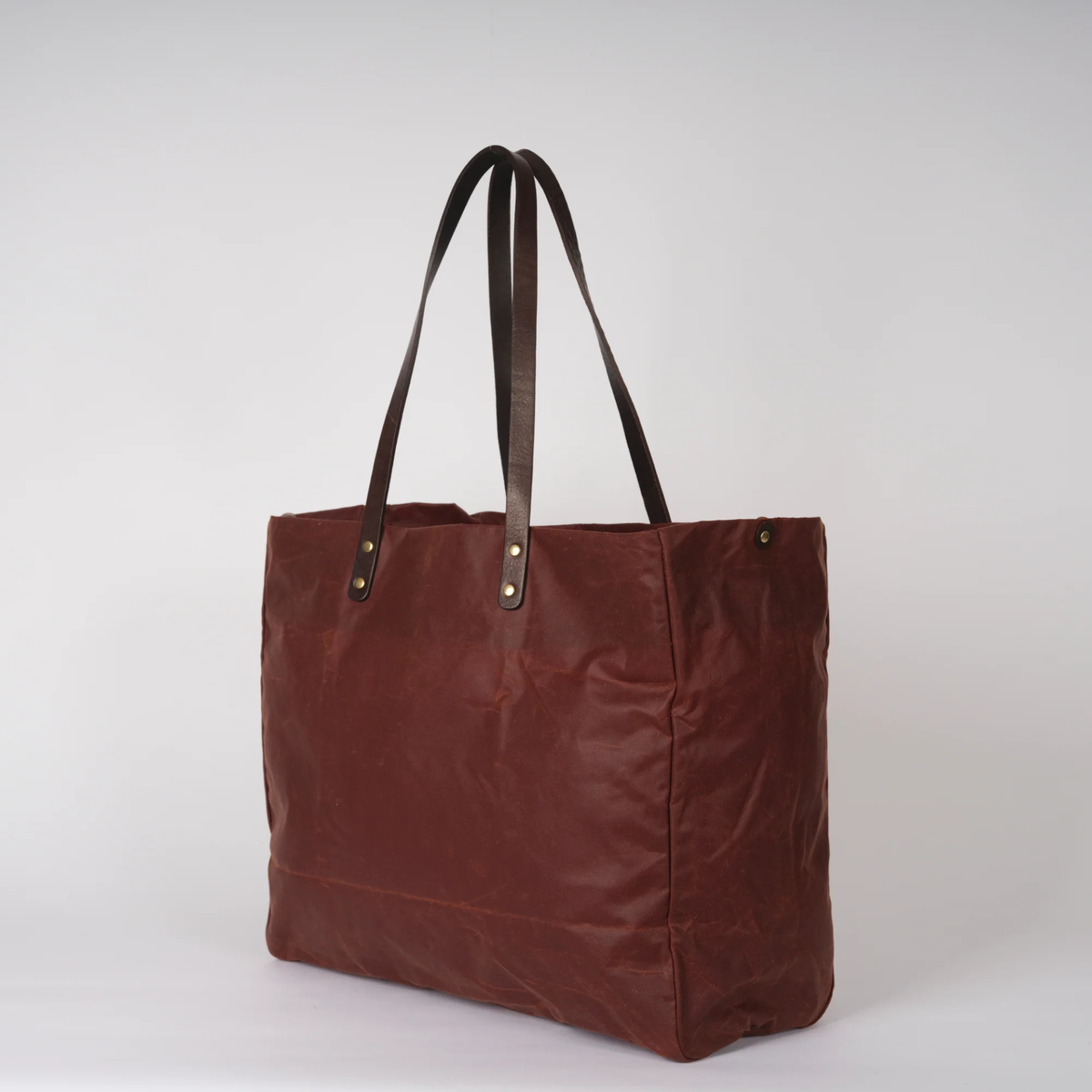 Brown tote bag with leather handles on a white background