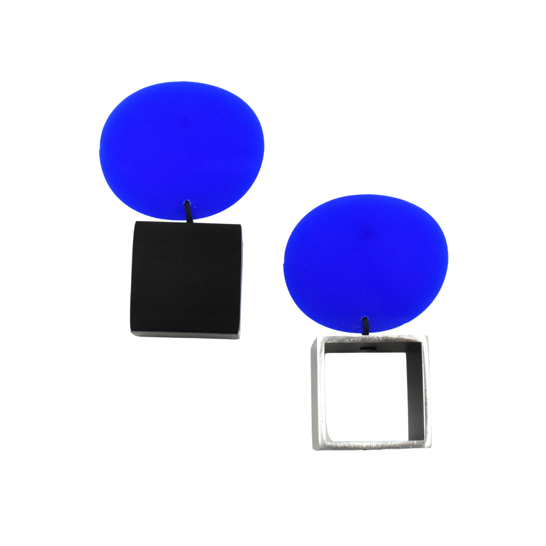 Pair of modern earrings; each features a bright blue oval disc above a geometric square—one black, one silver.