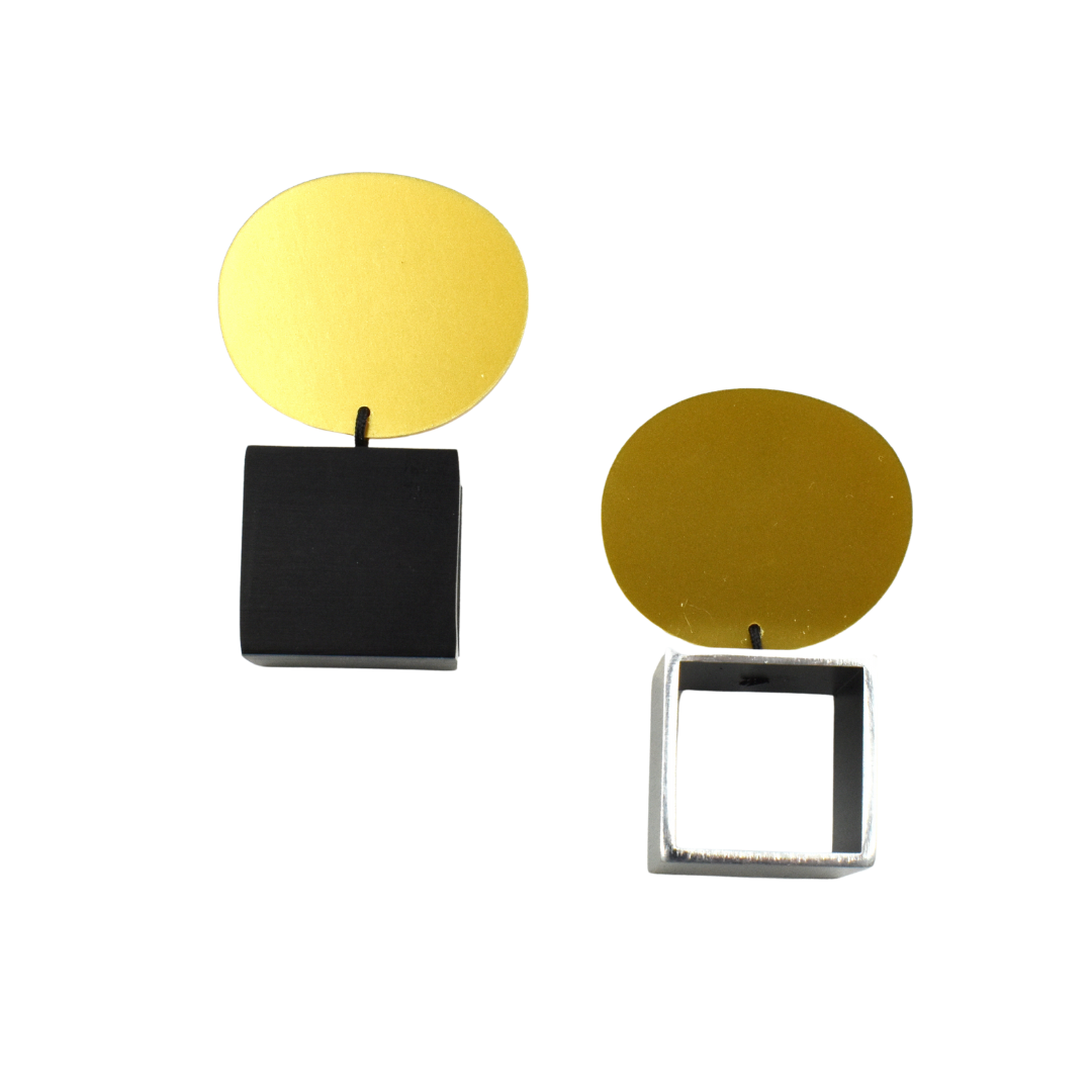 Pair of geometric earrings; one with black square and gold circle, the other with silver square frame and gold circle.