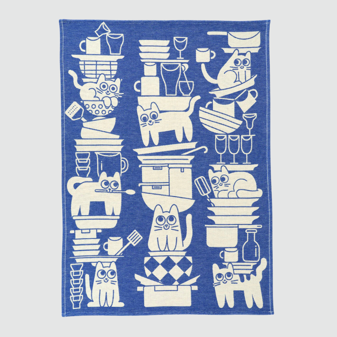 Blue towel with white cat and kitchen items pattern on a light gray background
