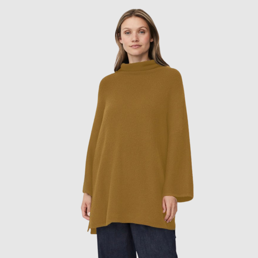 Woman wearing a mustard yellow poncho against a white background