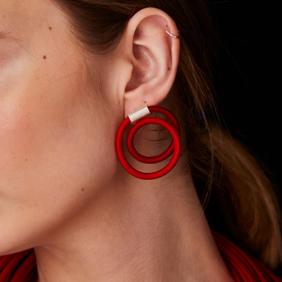 Red double-hoop earrings with a silver connector.