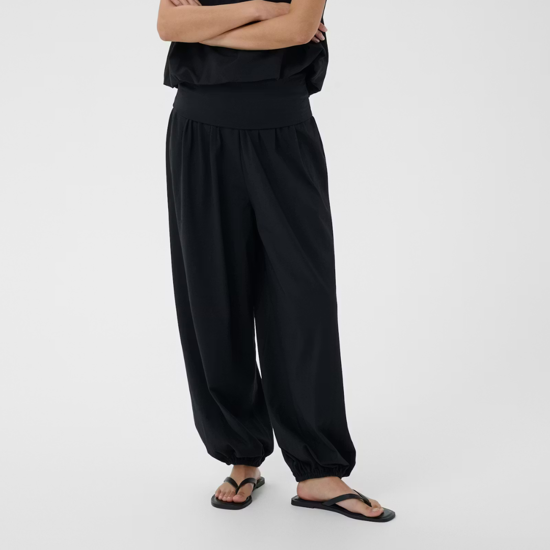 Person wearing black wide-leg pants on a white background