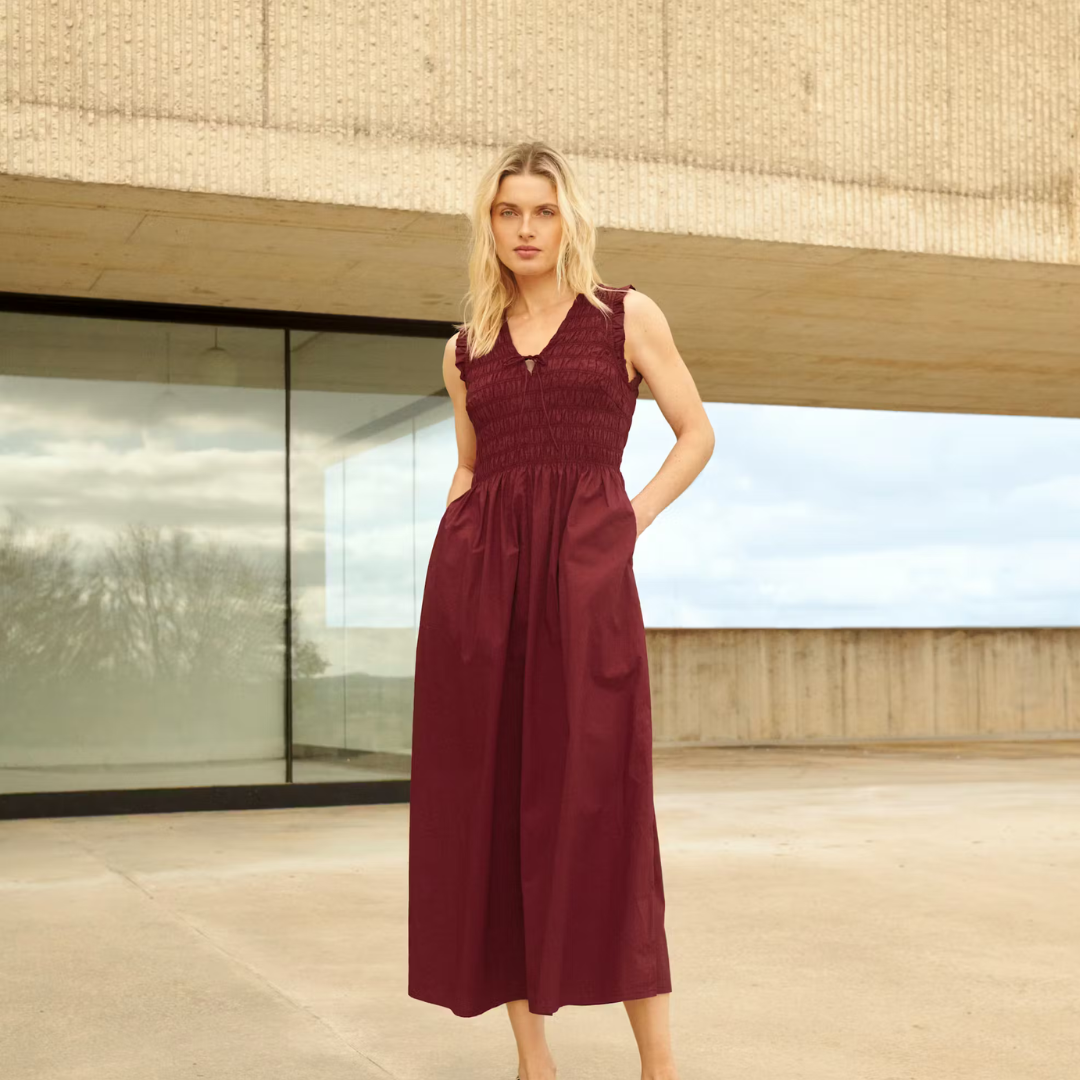 Woman in a burgundy dress standing in front of a modern building.