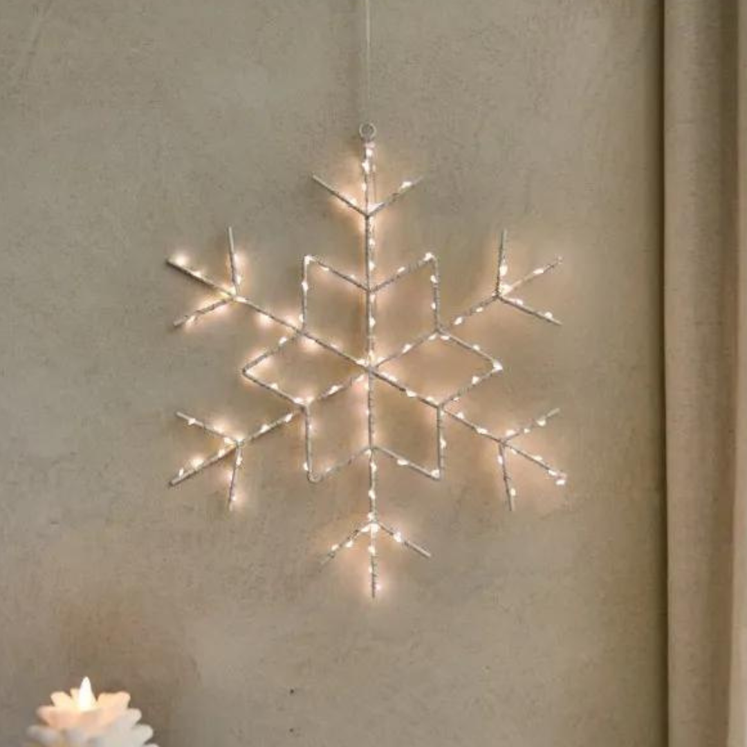 LED-lit wire snowflake wall decoration.  White metal frame with warm white lights.