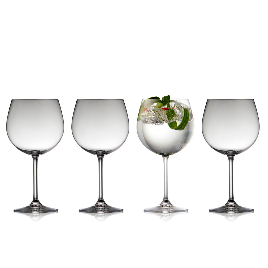 Gin and tonic in a balloon glass, flanked by two empty glasses.