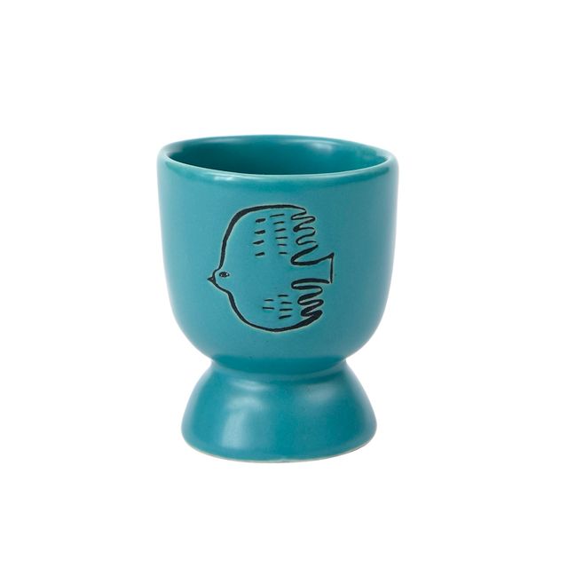 Turquoise egg cup with fish design on a white background