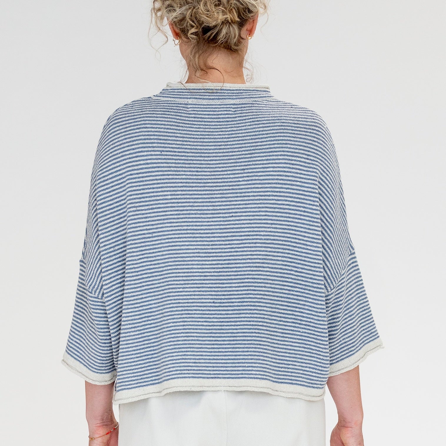 Person wearing a blue and white striped shirt on a plain background