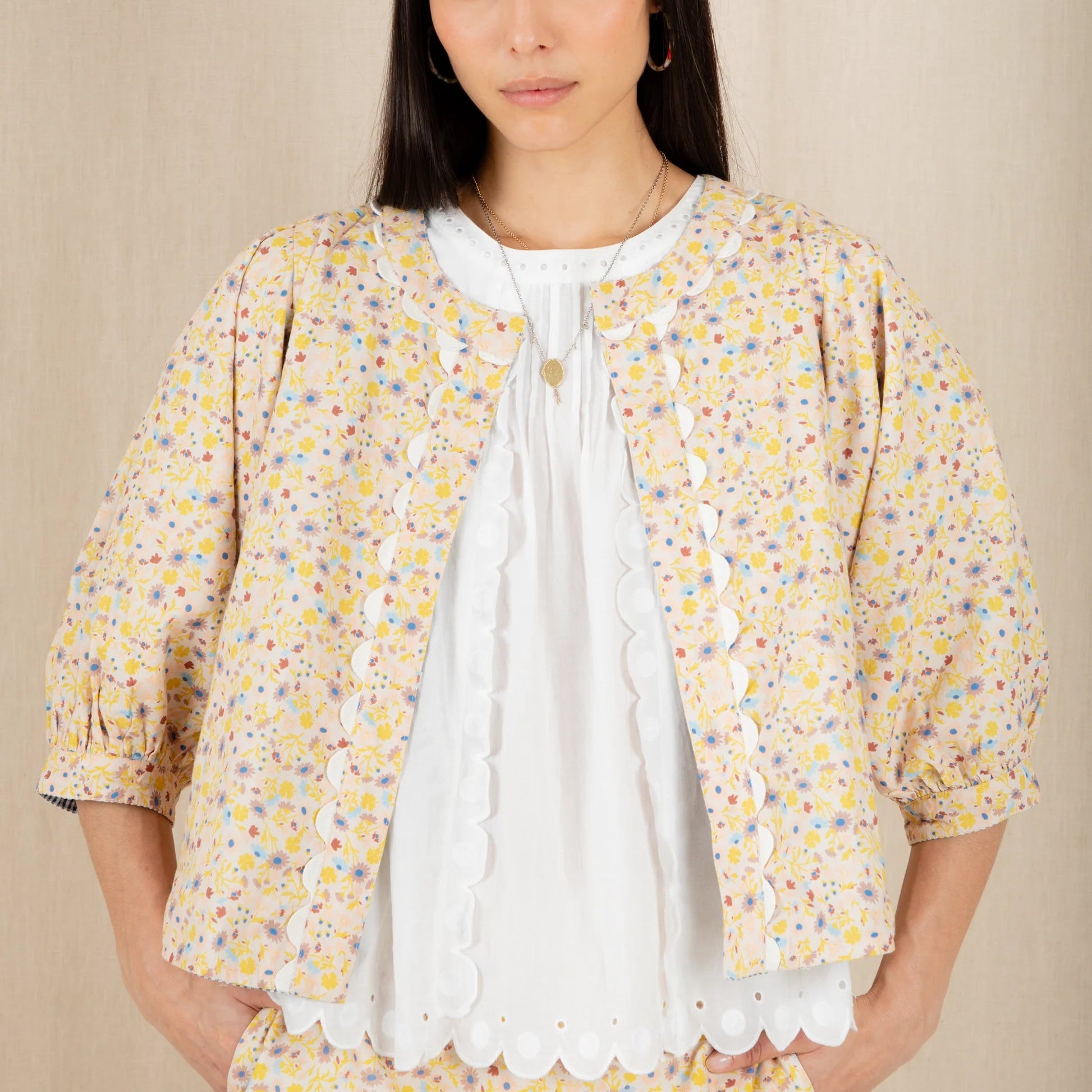 Woman wearing a yellow floral outfit with a beige background