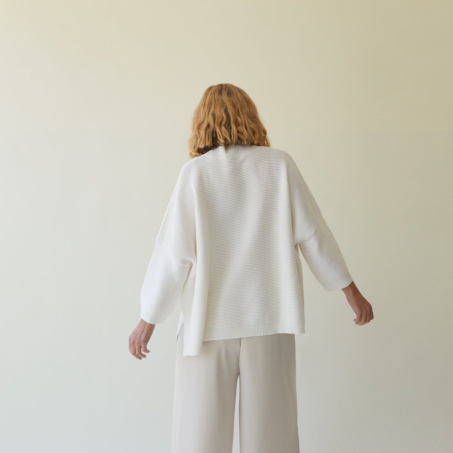 Off-white ribbed knit sweater with three-quarter sleeves, shown from the back.