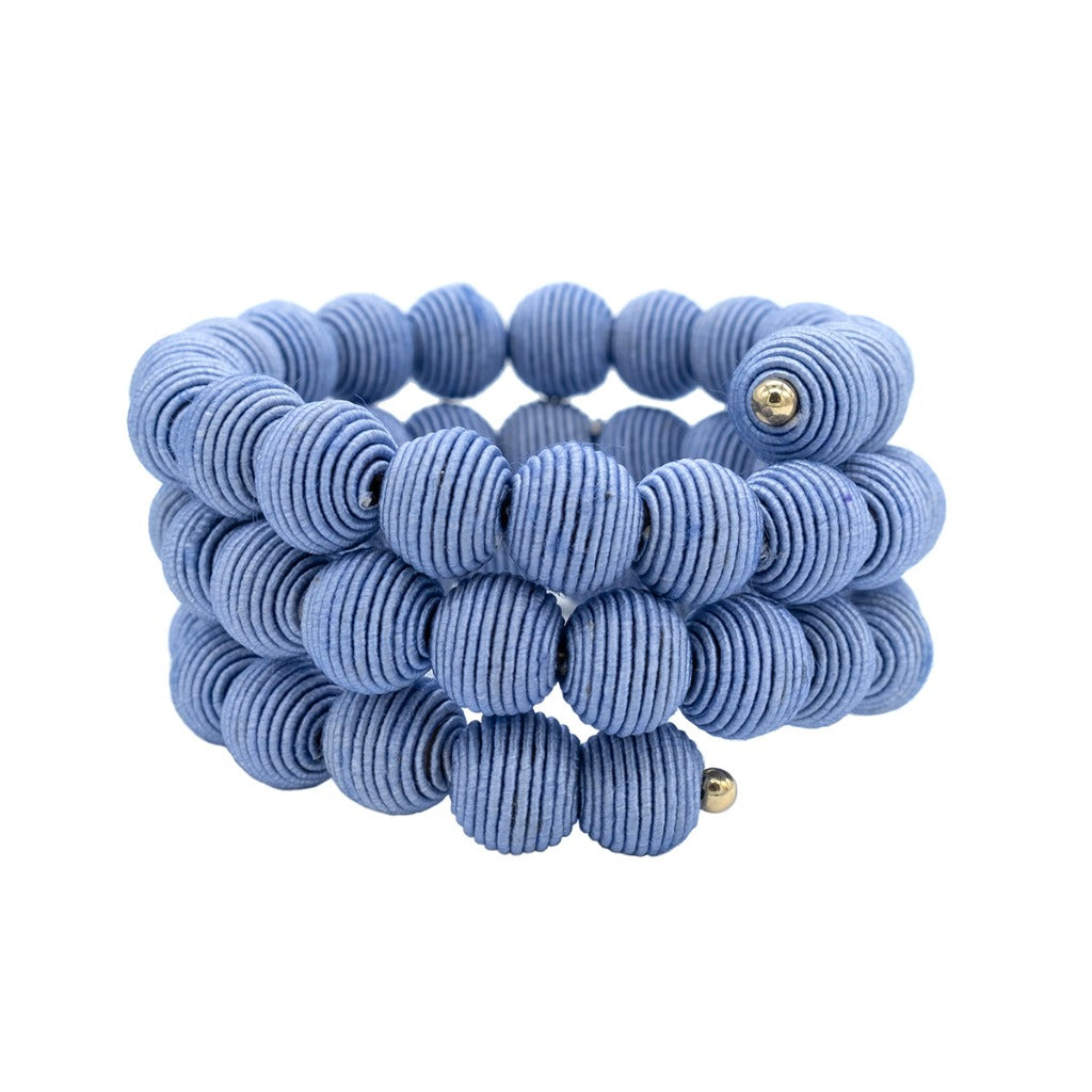 Triple-wrap bracelet of light blue, textured beads with small gold accents.