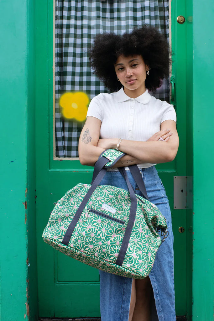 Green and pink floral-print duffel bag with dark gray straps.