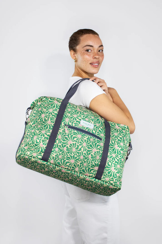 Green floral-print duffel bag with dark gray straps and zippered pocket.
