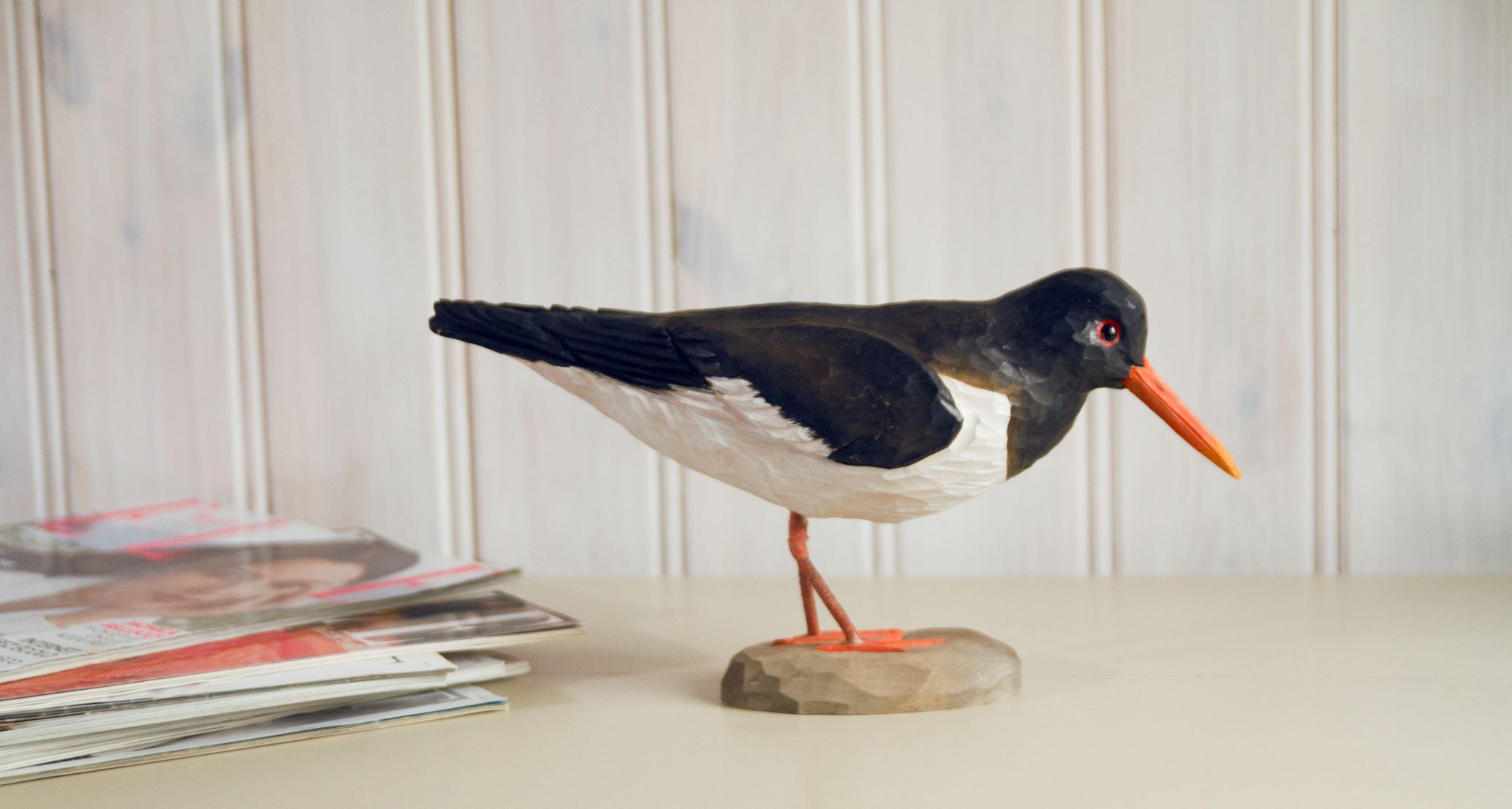Model of a bird on a wooden base with a white wall background