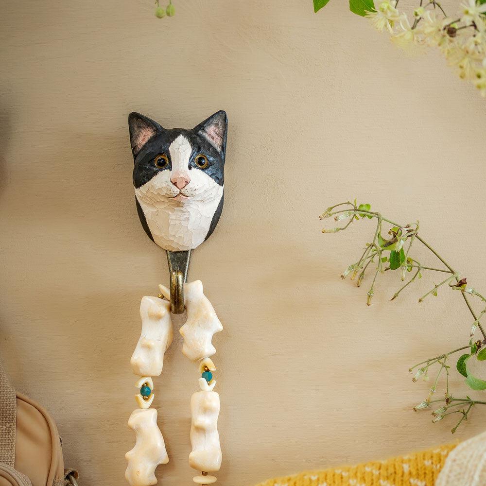 Cat-shaped wall hook with decorative elements on a beige wall.