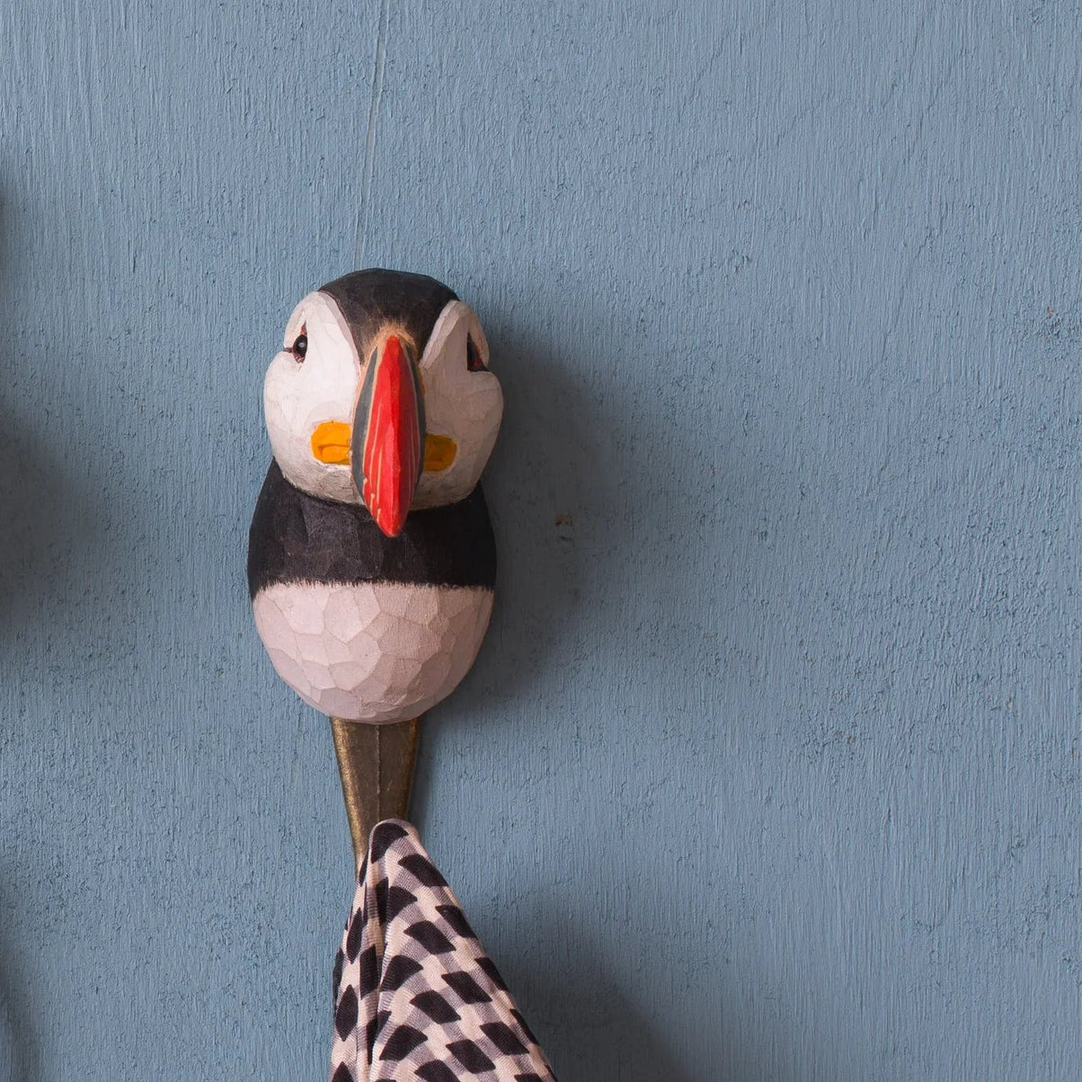 Three decorative animal-themed wall hooks on a blue wall.