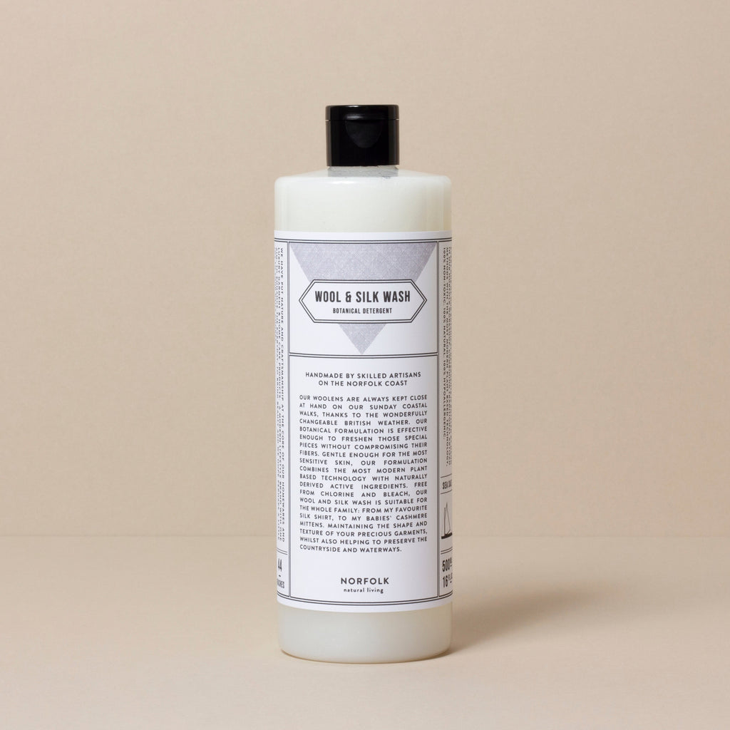 opaque white bottle with black top, containing Norfolk Natural Living 'Wool & Silk Wash' Botanical Detergent, with black and white ingredients and description label affixed