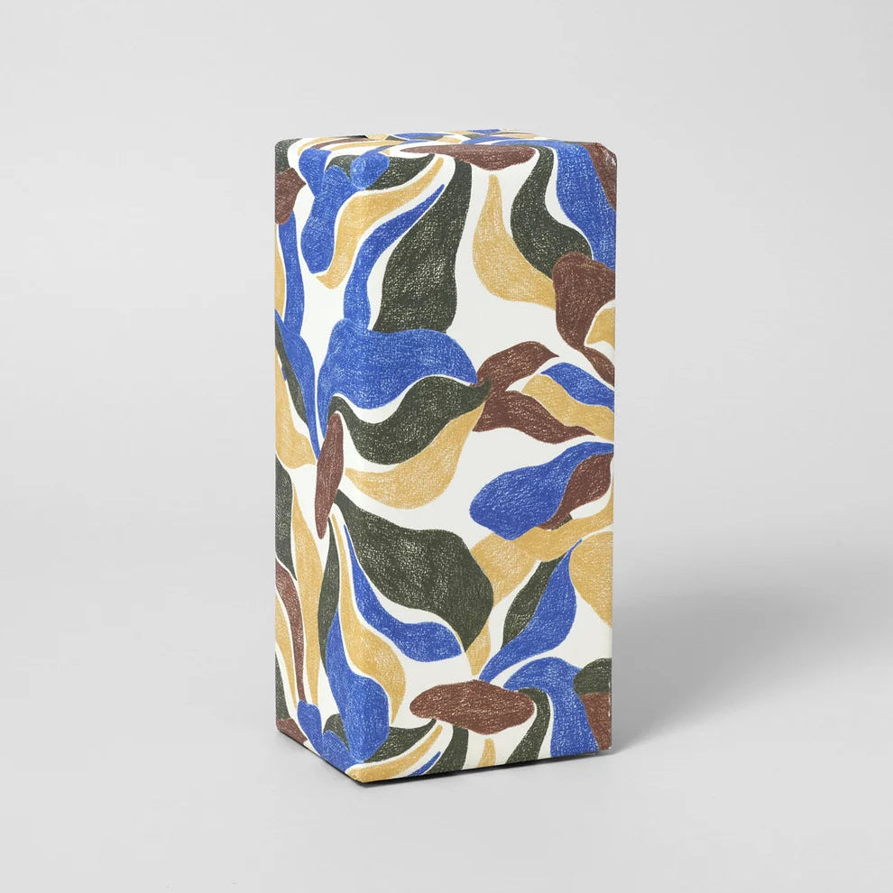 A rectangular box wrapped in white paper featuring a colorful abstract marbled pattern with blue, mustard yellow, olive green, and brown shapes, photographed on a light gray background.