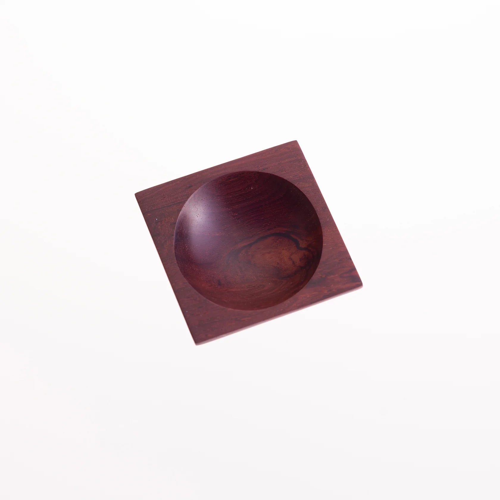 Dark reddish-brown square wooden bowl with a circular, scooped-out interior.