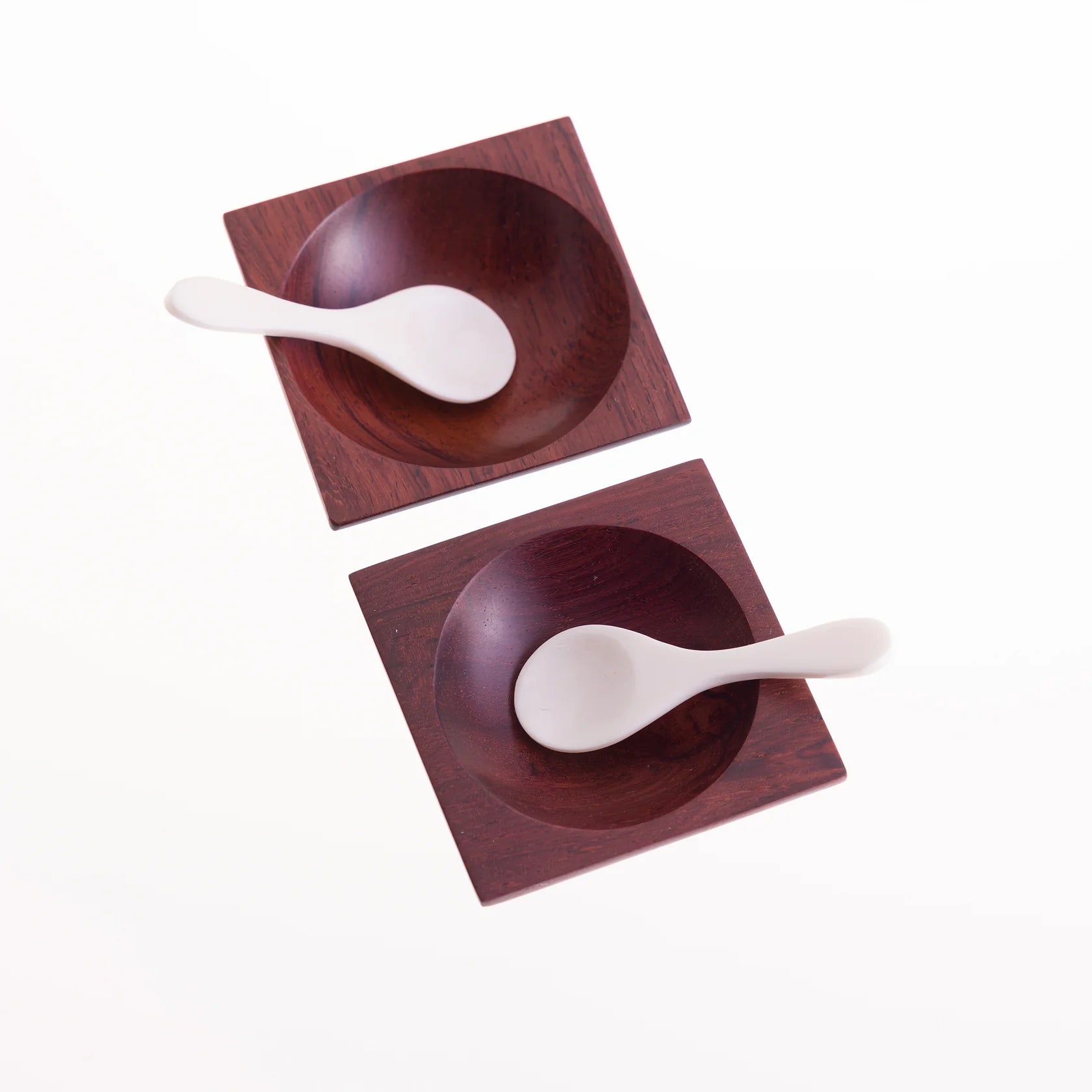 Two square wooden dishes containing small white spoons.