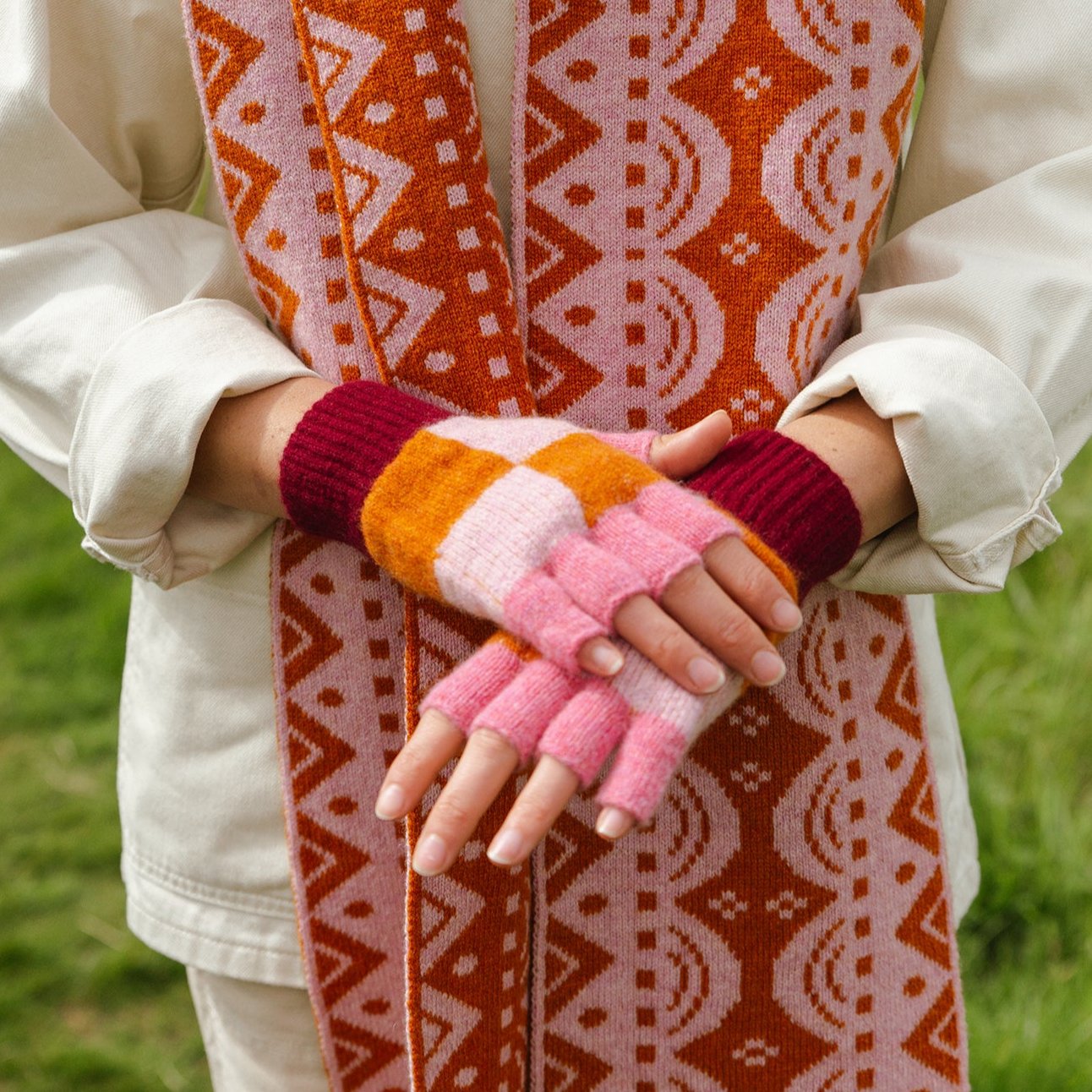 Pink, orange, and burgundy fingerless gloves and a matching patterned scarf.