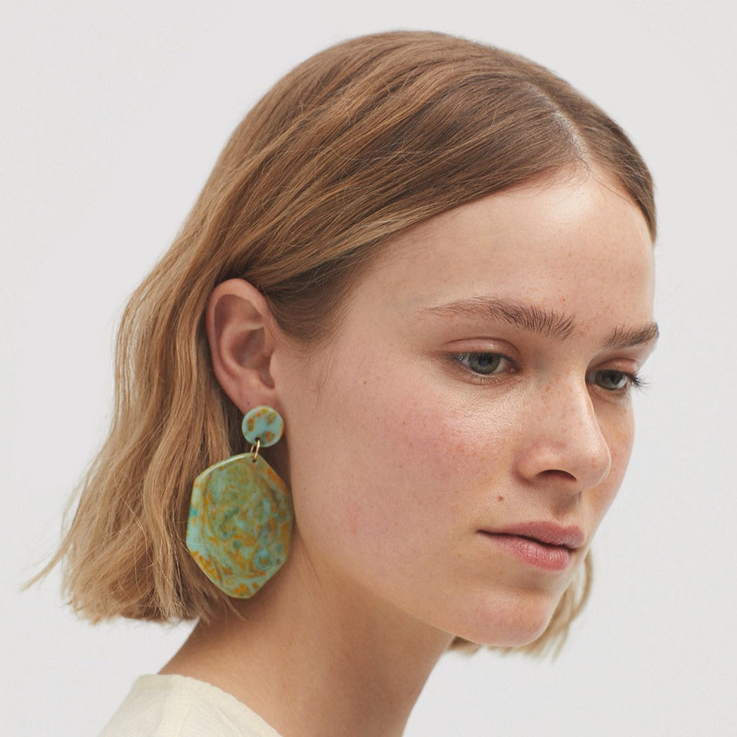 Teal and gold marbled hexagon-shaped statement earrings with a smaller teal disc accent.