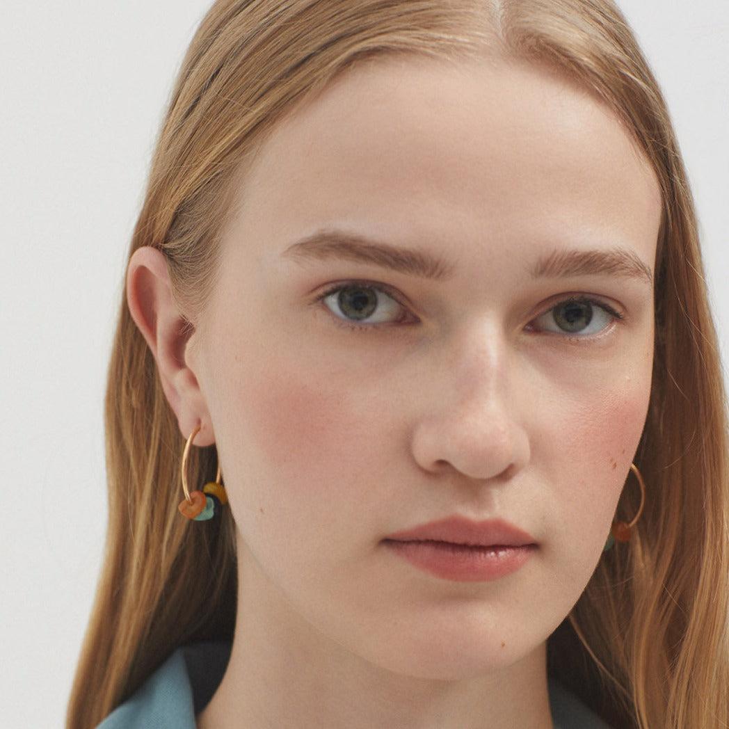 Gold hoop earrings adorned with small, multicolored stones.