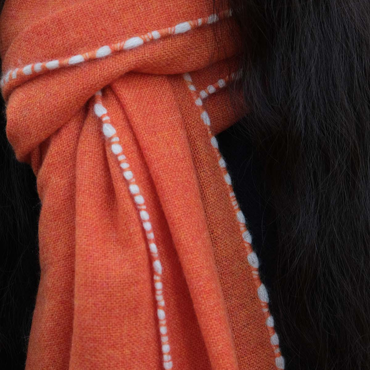 Close-up of an orange fabric with white stitching on a black background