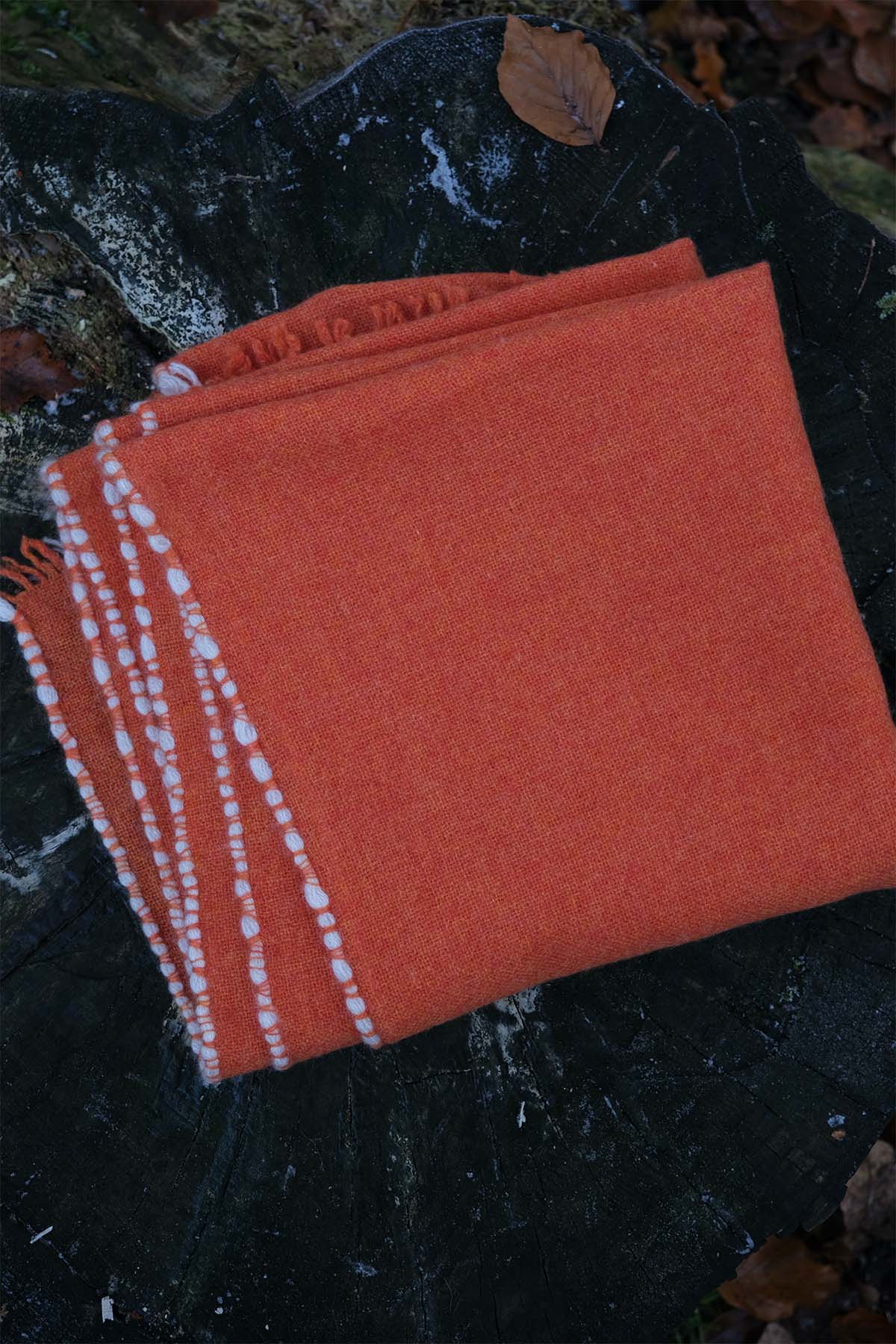 Orange towel with white border on a dark surface