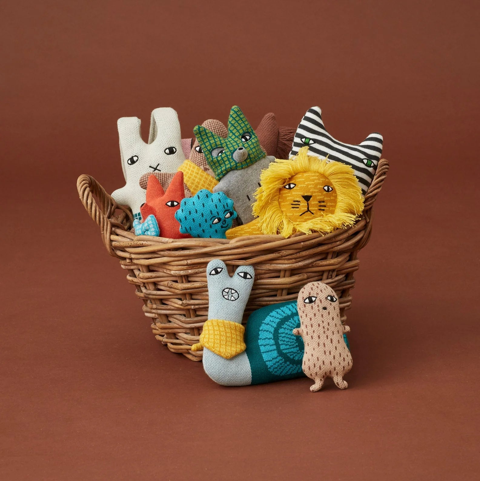 Wicker basket filled with colorful soft toys on a brown background