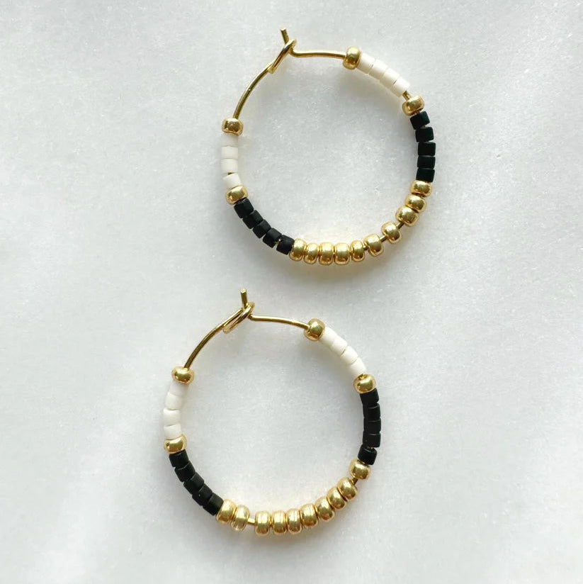 Gold hoop earrings adorned with black and white beads.