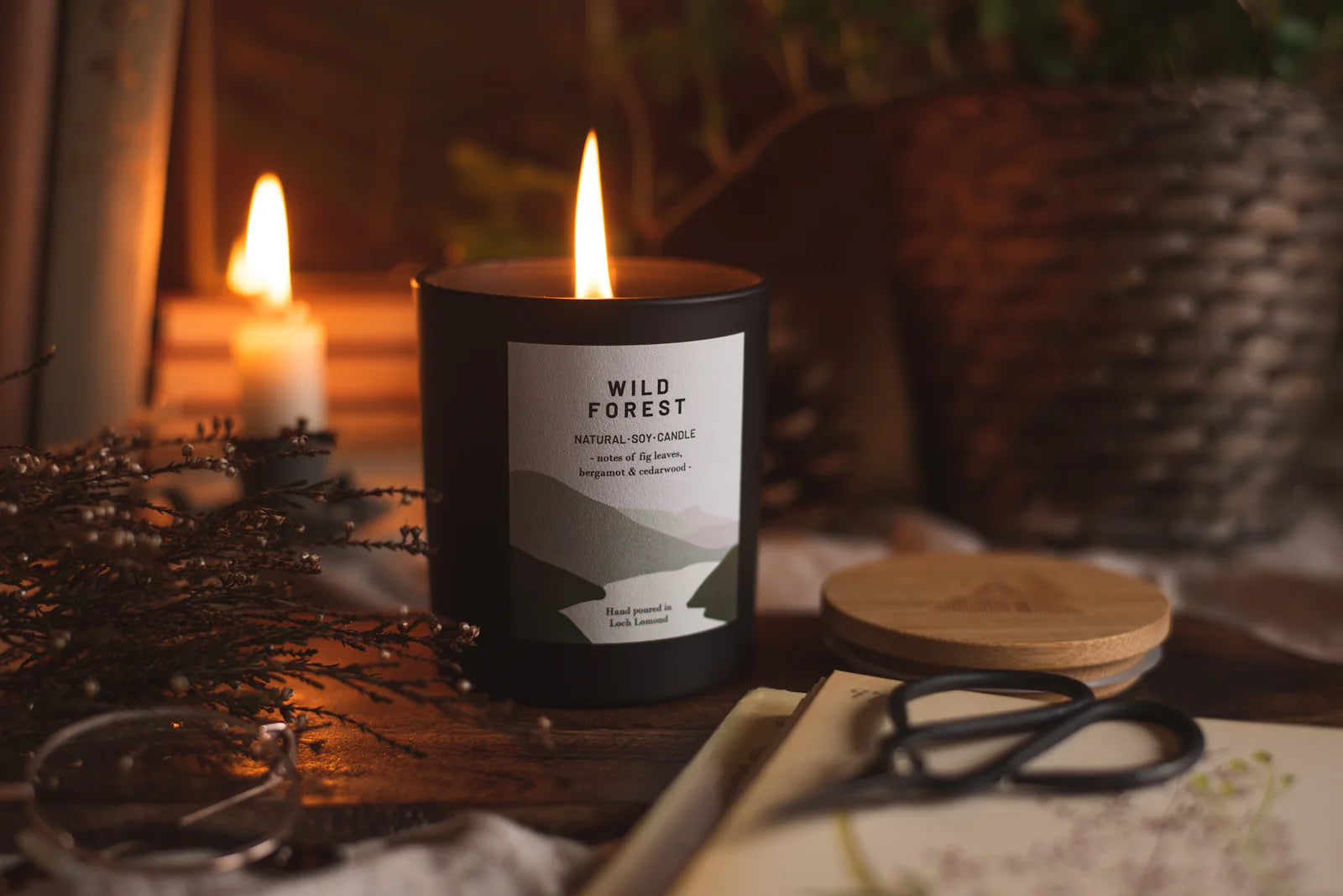 Lit black soy candle with "Wild Forest" label; notes of fig leaves, bergamot & cedarwood; hand-poured in Loch Lomond.