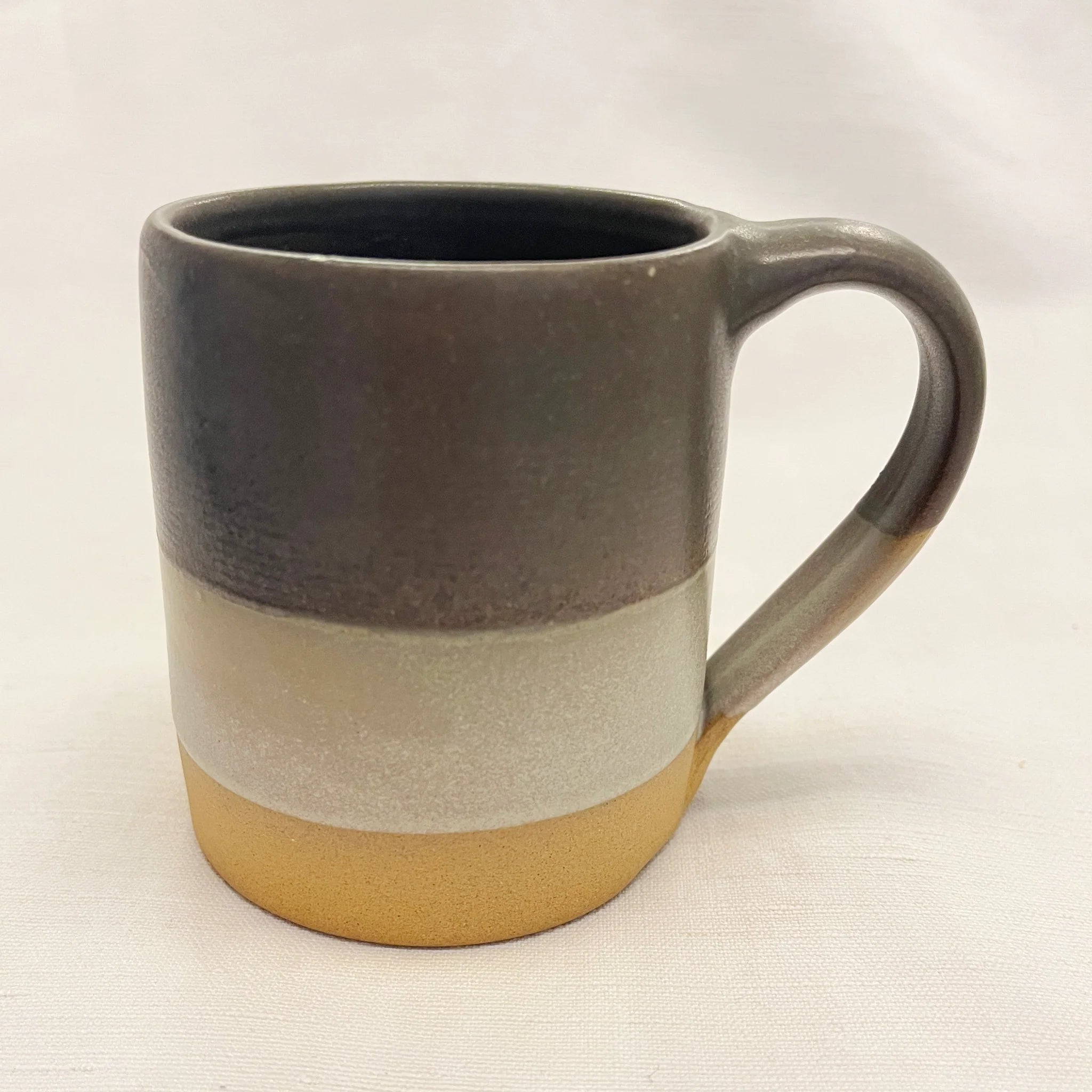 Stoneware mug with three horizontal bands of dark gray, light gray, and gold.