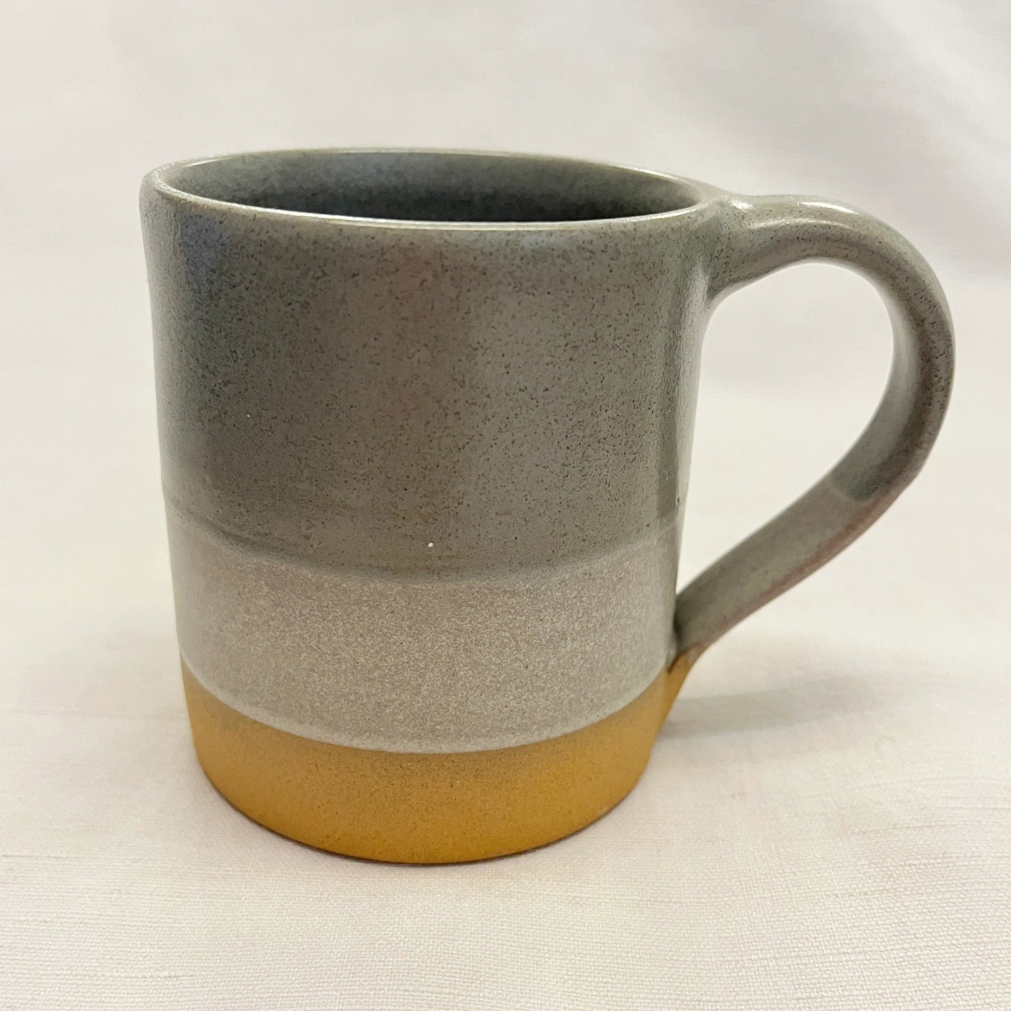 Stoneware mug with a grey, light grey, and mustard yellow speckled glaze.