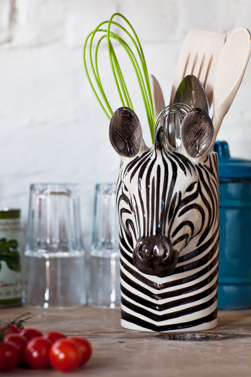 Black and white zebra-shaped ceramic utensil holder containing a whisk and wooden spoons.