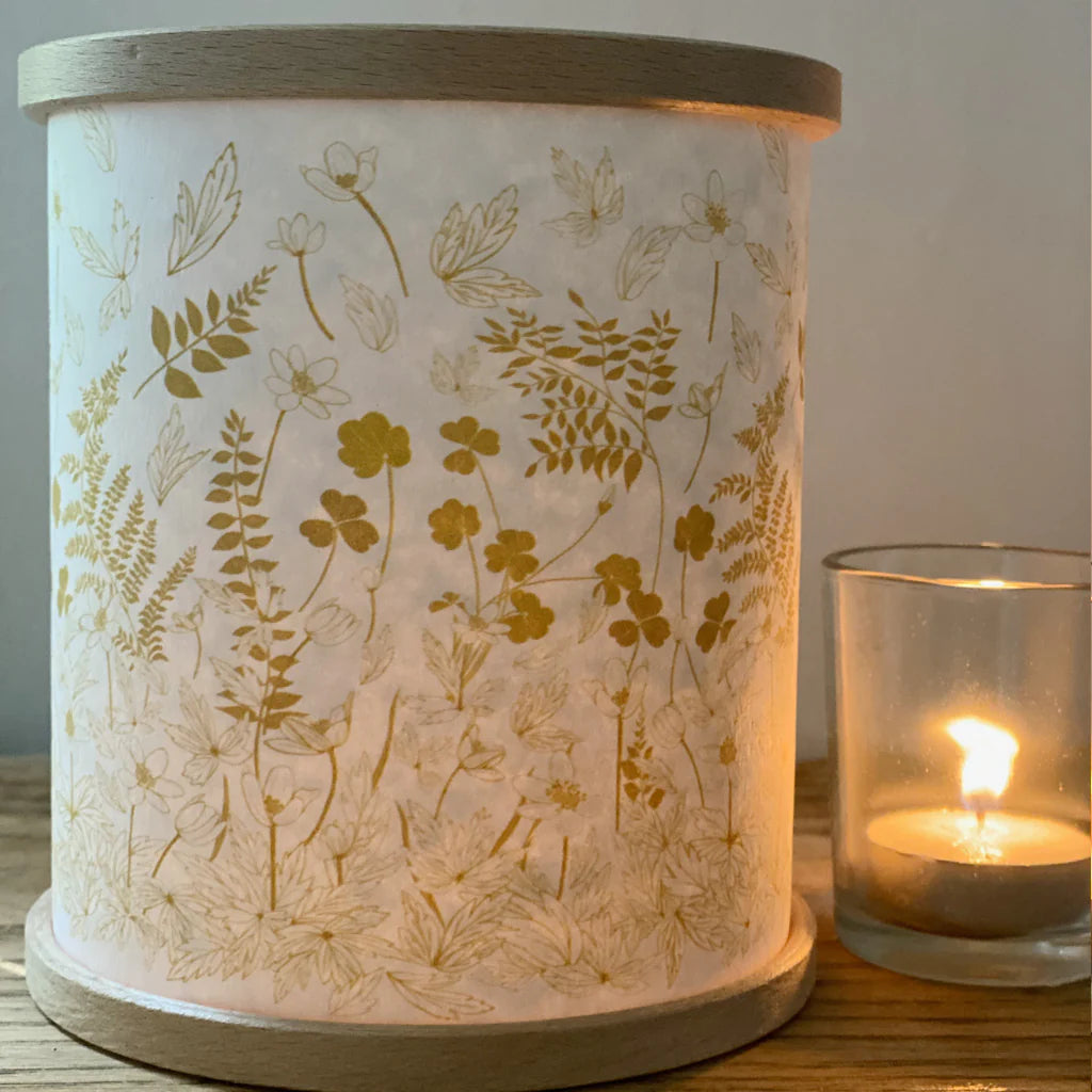 Cylindrical lampshade with wood base, featuring a gold floral pattern on off-white background.