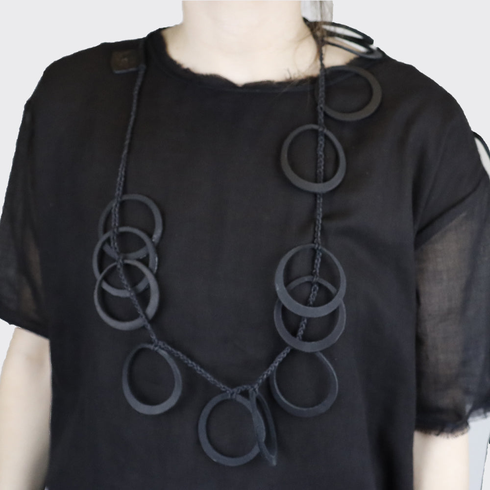 Black necklace featuring a series of interconnected, matte black circular elements on a thin black cord.