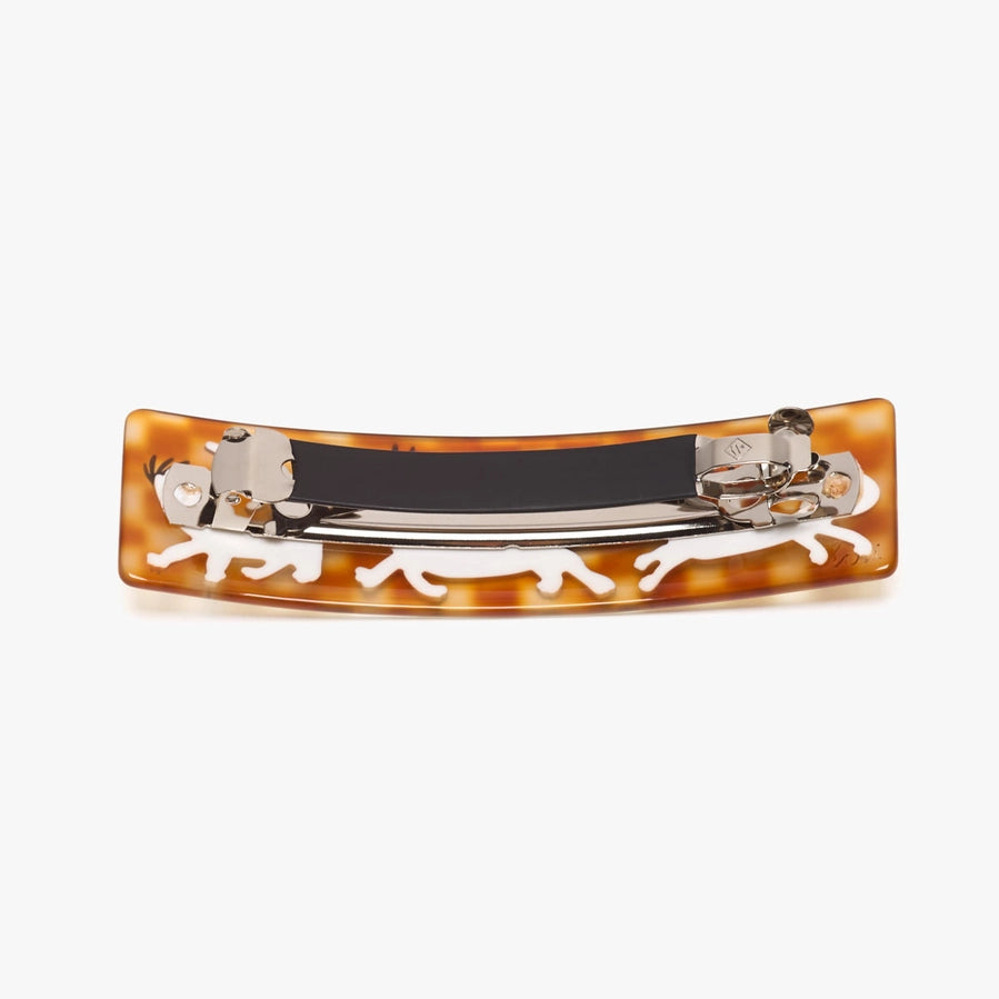 A curved tortoiseshell hair barrette with white enamel animal silhouettes and a silver metal clasp mechanism, shown from the back on a light gray background.