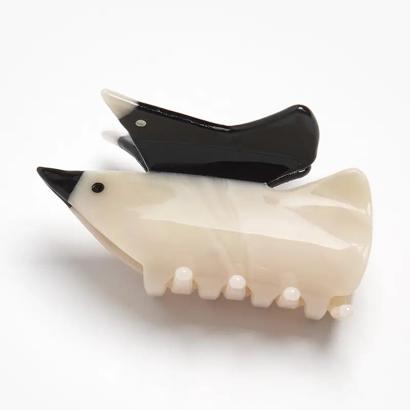 Two glossy bird-shaped hair claw clips on a white background, one in cream with a black beak and eye, and the other in solid black.