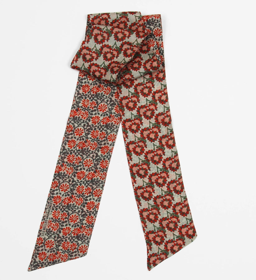 A patterned silk necktie with a red and orange floral motif on a beige and gray base, folded to show both sides of the design against a light gray background.
