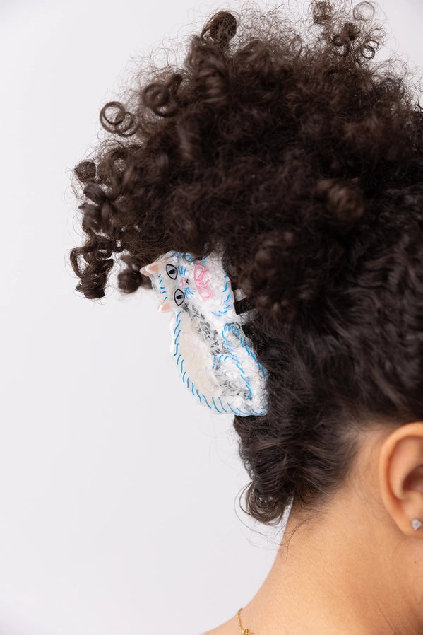 Close-up of a person with curly hair wearing a decorative hair clip on a white background