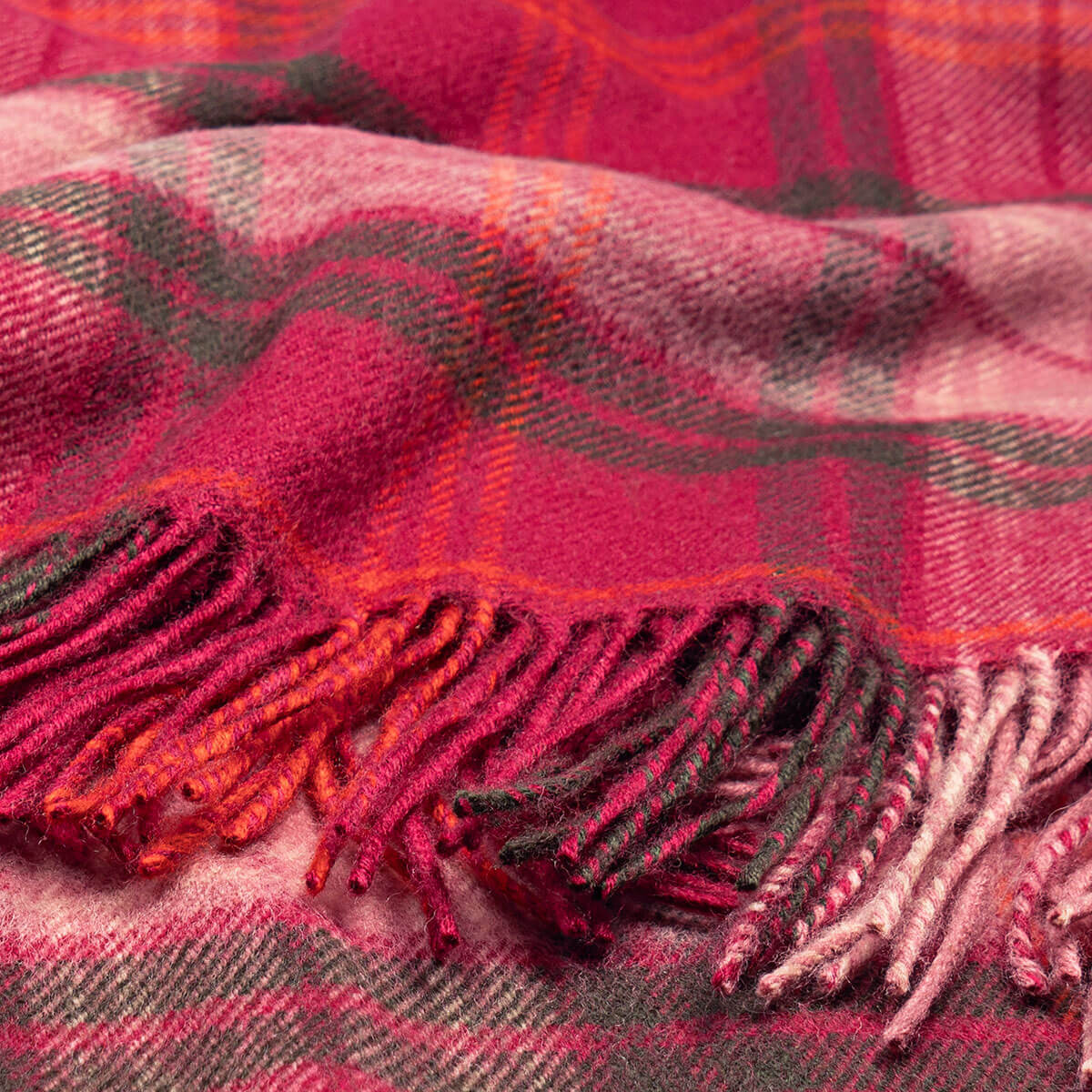 Close-up of a red and black plaid blanket with tassels