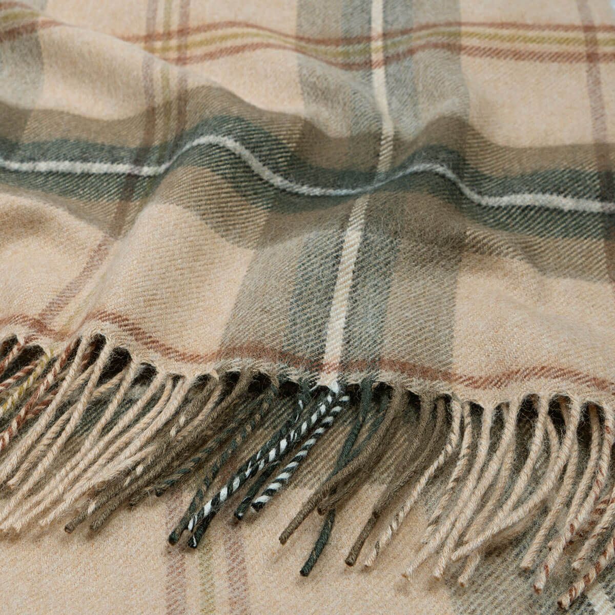 Beige and green plaid throw blanket with fringed edges.